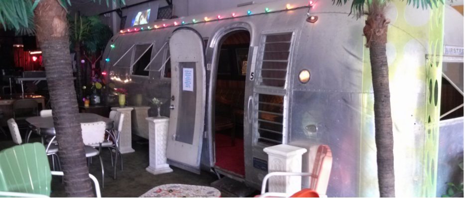 The silver Airstream trailer parked inside Fifi’s lounge among palm trees and string lights