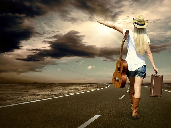 Musician with a guitar on a country road
